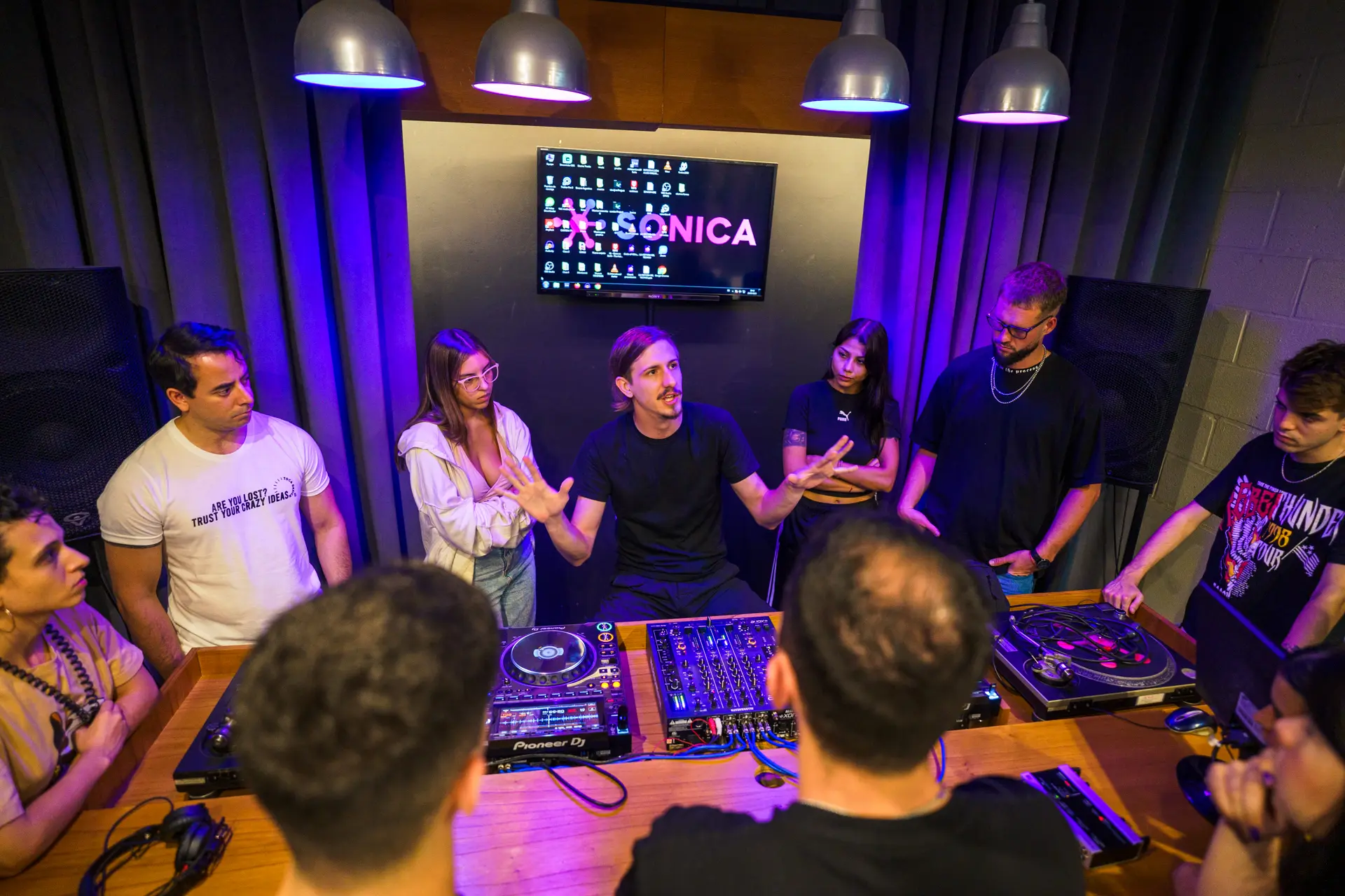 Alumnos y docente conversando alrededor de los equipos en el aula de DJ