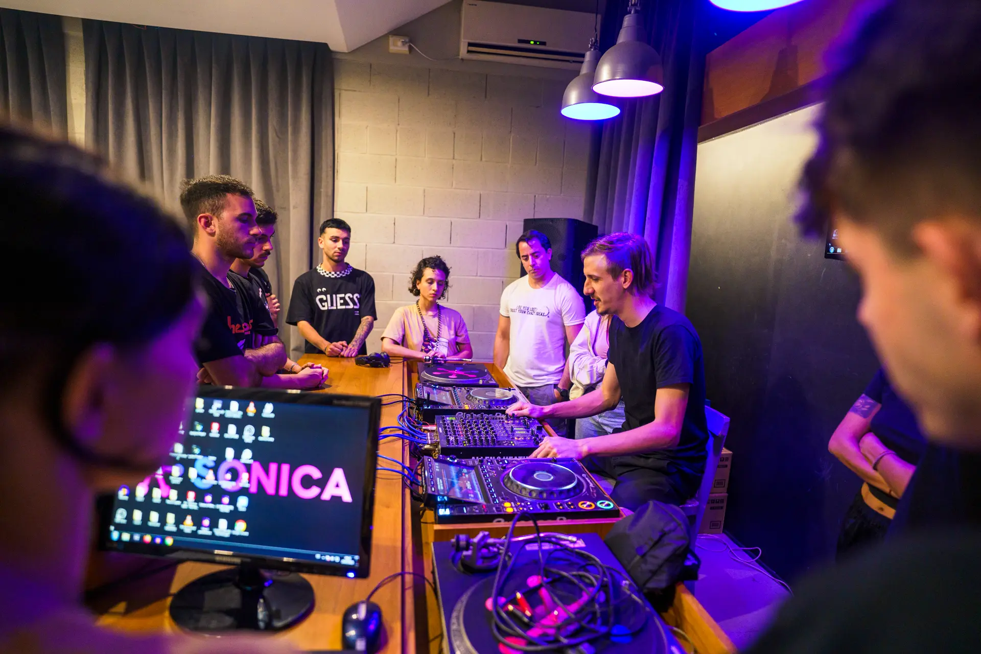Alumnos de DJ junto a la cabina, con la computadora en primer plano